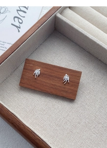 Macro shot of S999 sterling silver swallow stud earrings on a wooden display stand