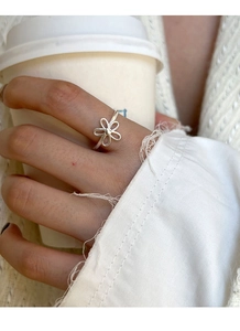 Detailed close-up of a minimalist hollow flower ring in S925 sterling silver on a hand