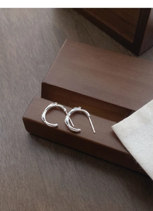 Detailed close-up of S925 sterling silver earrings with bamboo-style texture on wood