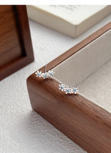 Gros plan détaillé des boucles d'oreilles S999 en argent avec trois fleurs et pierres bleues