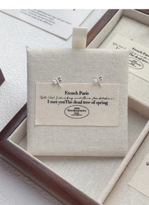 Detailed macro view of S999 sterling silver dragonfly stud earrings on beige fabric
