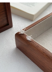 Close-up of S999 sterling silver swallow stud earrings on a wooden jewelry box