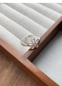 Macro shot of minimalist S925 sterling silver hollow flower open ring on wood tray