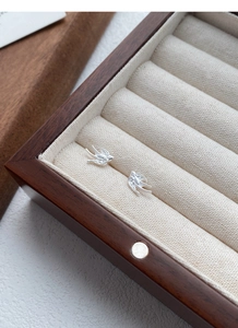 Detailed macro view of S999 sterling silver swallow stud earrings in a wooden jewelry box
