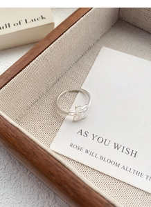 Detailed view of an S925 sterling silver open flower ring on a rustic wooden tray