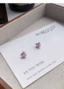 Gros plan sur des boucles d'oreilles en argent S999 avec pierres roses en forme de cœur