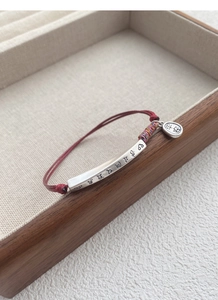 Detailed macro view of S999 silver tube and Ping An pendant on a red woven bracelet