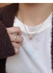 Gros plan du collier pendentif feuille de blé dorée et de la bague en diamant assortie