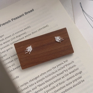 S999 sterling silver swallow stud earrings displayed on a rustic wooden card holder