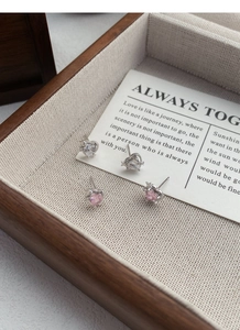 Gros plan de boucles d'oreilles cœur en argent S999 avec détails d'étoiles sur bois
