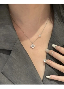 Detail view of a sterling silver clover necklace with zircon inlay on a model neck