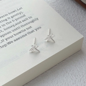 Minimalist S999 sterling silver dragonfly stud earrings on a vintage book page