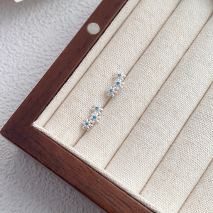 Boucles d'oreilles marguerites en argent S999 avec pierres bleues dans un écrin à bijoux