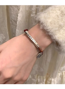 Detail of red braided bracelet featuring S999 silver engraved tube and colorful silk thread