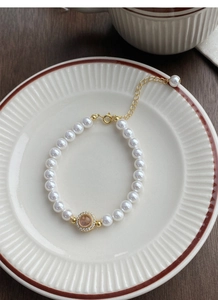 Detail of S925 silver pearl bracelet with pink gemstone pendant on ceramic plate