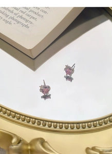Détail de boucles d'oreilles en argent S999 avec cœur rose et motif d'étoile