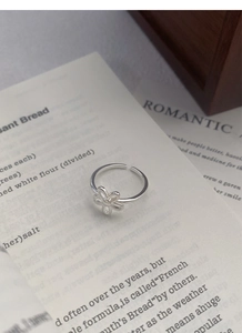 Macro view of a 925 sterling silver hollow flower ring placed on vintage book pages