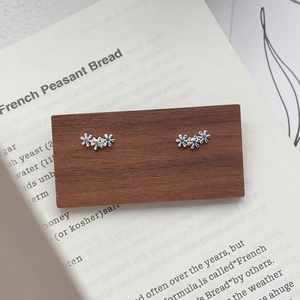 Boucles d'oreilles fleurs en argent fin S999 avec pierres bleues sur support en bois
