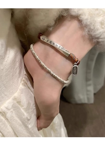 Detail view of ethnic S999 silver bar bracelet with red braided rope on a model's wrist