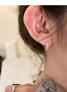 Detail of silver floral stud earrings featuring three stacked flowers with white zircon stones
