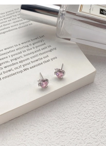 Gros plan de boucles d'oreilles en argent cœur rose avec détail étoile sur fond texturé