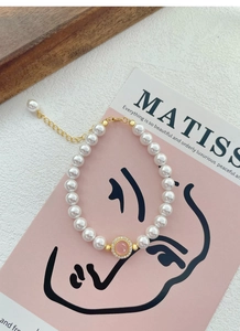 Macro detail of a pearl bracelet featuring a pink gemstone pendant and gold chain