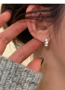 Close-up of sparkling S925 sterling silver huggie earrings with pavé crystals on ear