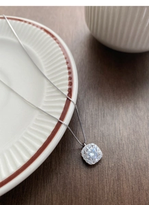 Macro detail of S999 silver sugar cube pendant necklace with sparkling zircon on wood