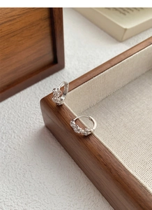 Detail of silver S925 floral hoop earrings featuring three small hollow carved flowers