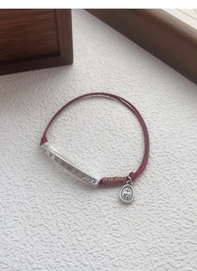 Detailed shot of S999 silver bar bracelet with red braided cord and Pingan charm