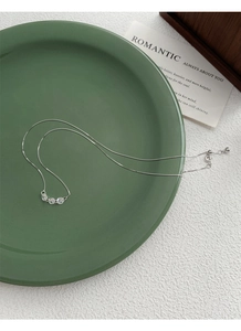 Détail du collier en argent S925 avec trois zircons posés sur un plateau vert