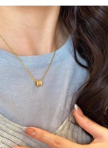 Gros plan du pendentif épi de blé doré sur chaîne en argent S925 porté par un mannequin