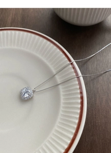 Detail of S999 sterling silver necklace with halo square zircon pendant on ceramic dish