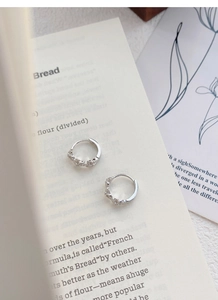 Detail of S925 sterling silver flower hoop earrings with zircon on a vintage book