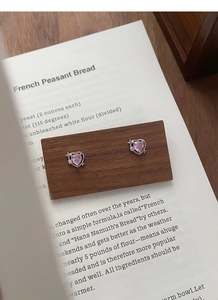 Détail de boucles d'oreilles cœur rose en argent S999 avec étoile sur bloc de bois