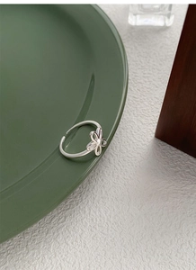 Close-up of S925 sterling silver hollow flower ring on green ceramic plate detail
