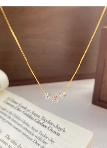 Vue macro d'un collier en argent S925 avec trois zircons ronds sur une chaîne box dorée