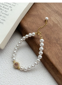 Detail of S925 silver bracelet with round white pearls and a pink stone pendant
