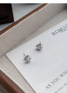 Détail de boucles d'oreilles cœur en argent S999 avec étoile sur carte de présentation