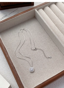 Close-up of S999 sterling silver square zircon pendant on a beige jewelry lining