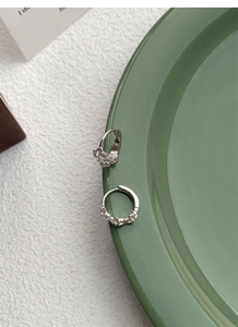 Macro detail of S925 sterling silver flower hoop earrings with zircon on ceramic tray