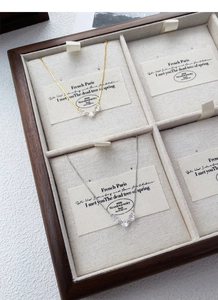 Détail de colliers or et argent avec cinq zircons brillants dans une boîte en bois chic