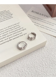 Detailed macro view of S925 sterling silver floral hoop earrings on a romantic card