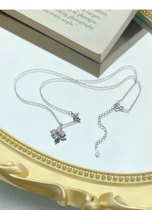 Macro shot of S925 sterling silver clover necklace with zircons on a gold mirror