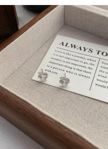 Détail de boucles d'oreilles cœur et étoile en argent S999 sur présentoir élégant