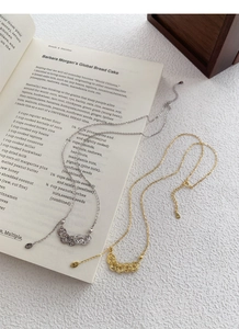 Macro detail of S925 sterling silver and 18K gold plated coin necklaces on book