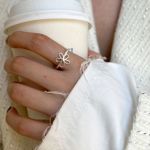 Elegant S925 sterling silver hollow flower open ring worn on a finger with a coffee cup