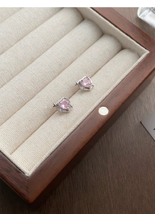 Vue macro de boucles d'oreilles cœur en argent avec pierres roses et détails d'étoiles