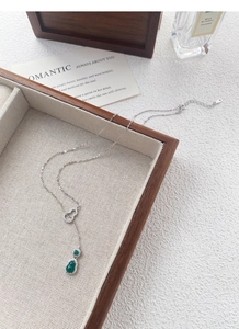 Dettaglio macro della collana in argento S925 con gemma verde e scatola in legno