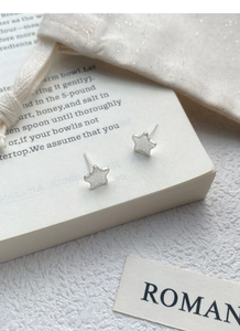 Macro detail of star-shaped S999 sterling silver studs with textured surface finish